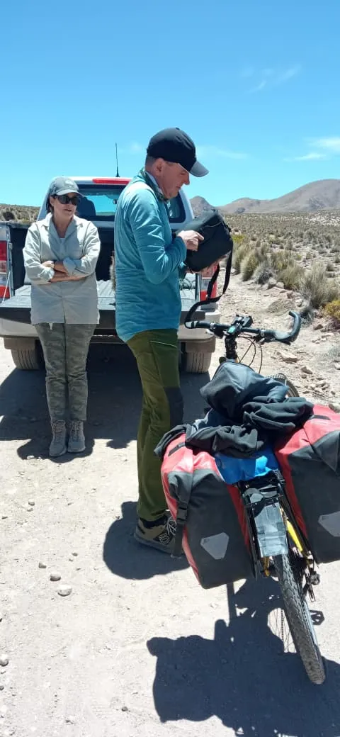 Ciclista bikepacker preparando su bicicleta cargada con alforjas junto a la camioneta