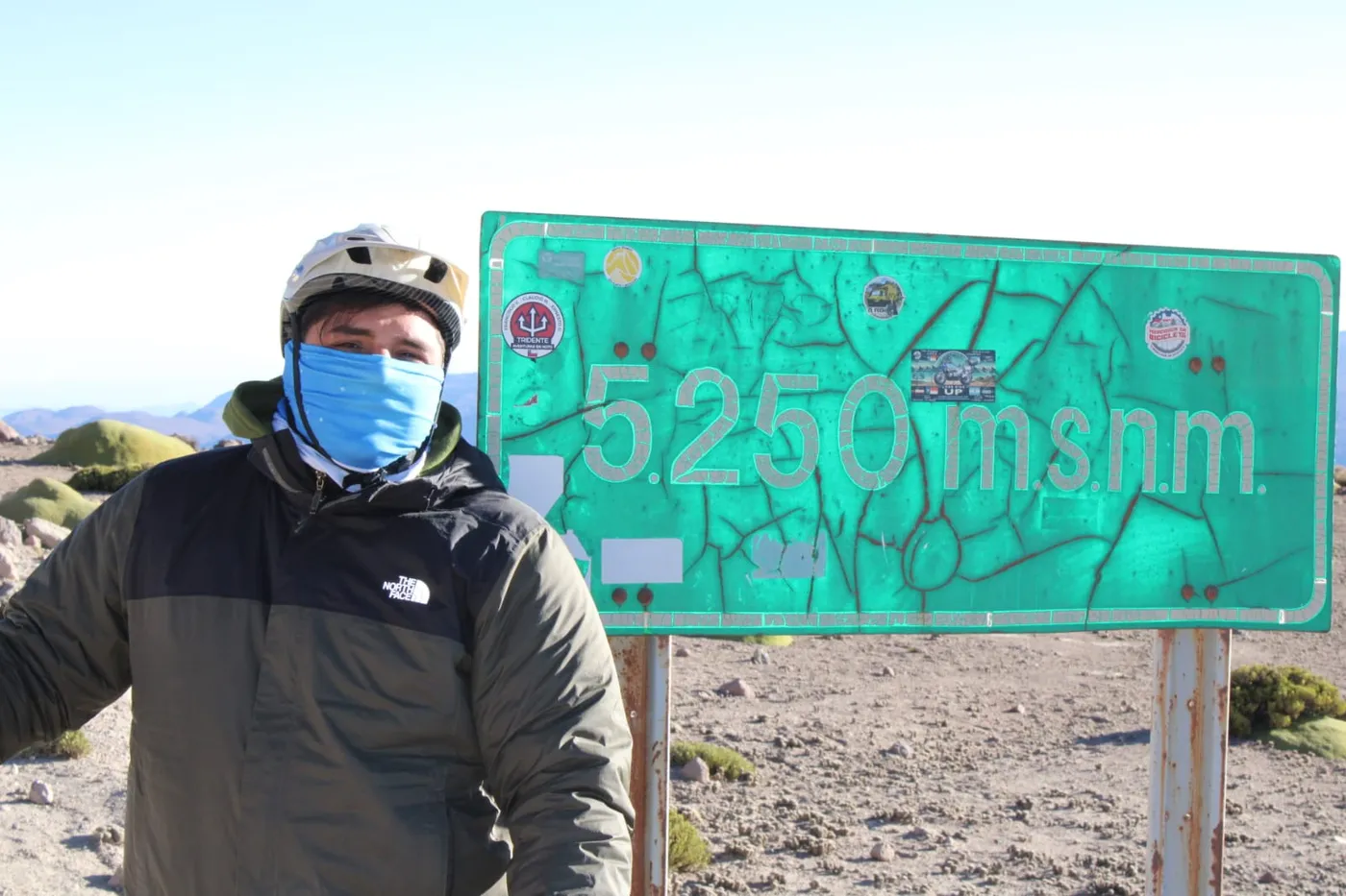 Ciclista posando junto al letrero de los 5.250 m.s.n.m.