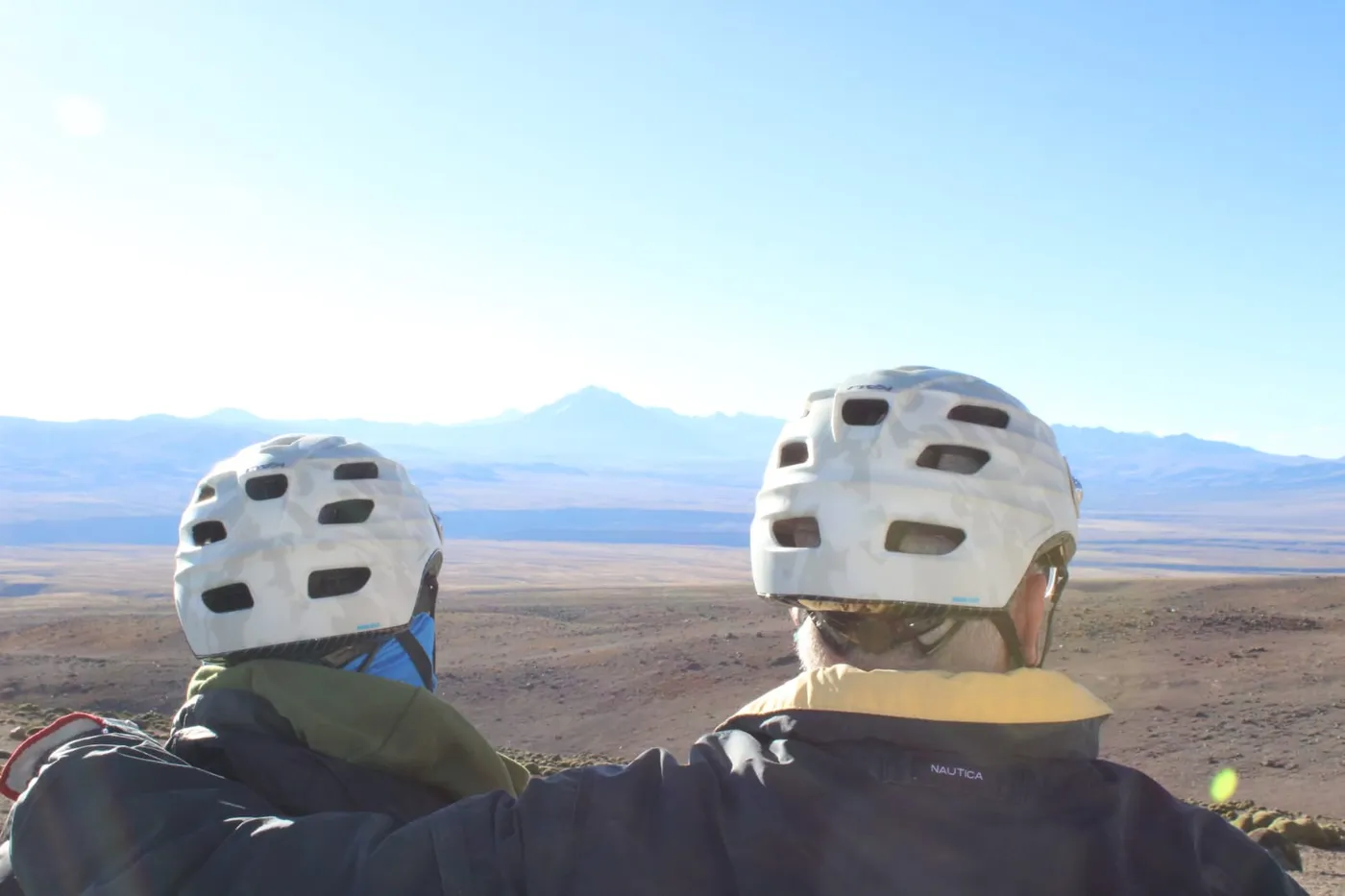 Dos ciclistas abrazados mirando un volcán nevado a la distancia