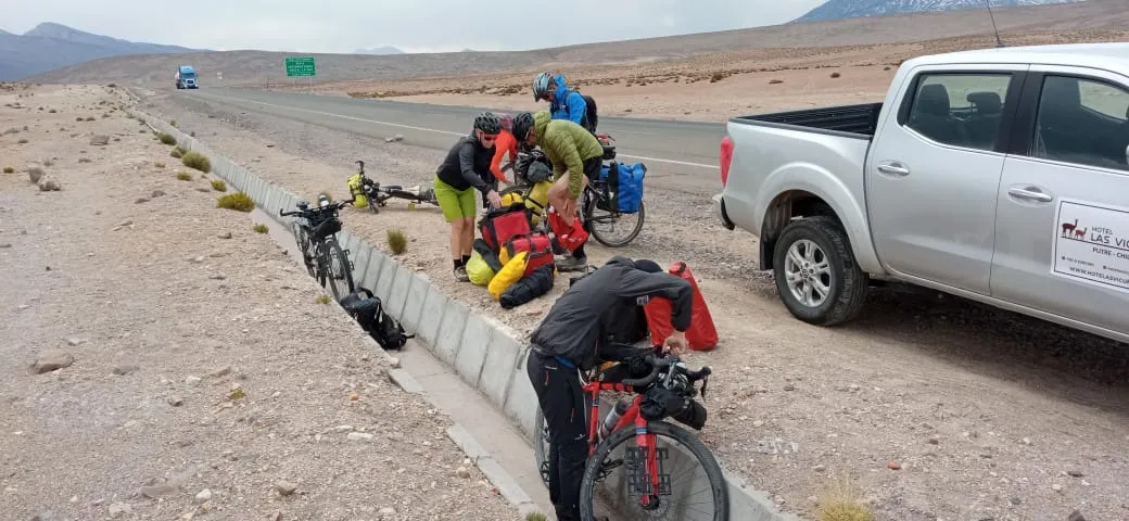 Grupo de ciclistas bikepackers acomodando su equipaje junto a la carretera, camioneta de apoyo
