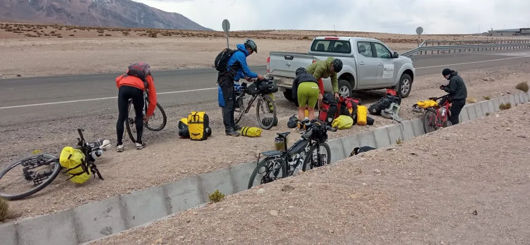 Grupo de ciclistas bikepackers preparando sus bicicletas y alforjas junto a la carretera