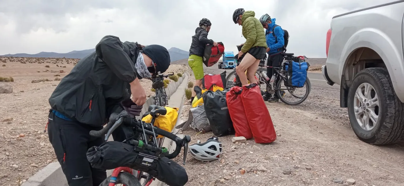 Grupo de cicloturismo empacando el equipaje junto a la ruta, altiplano