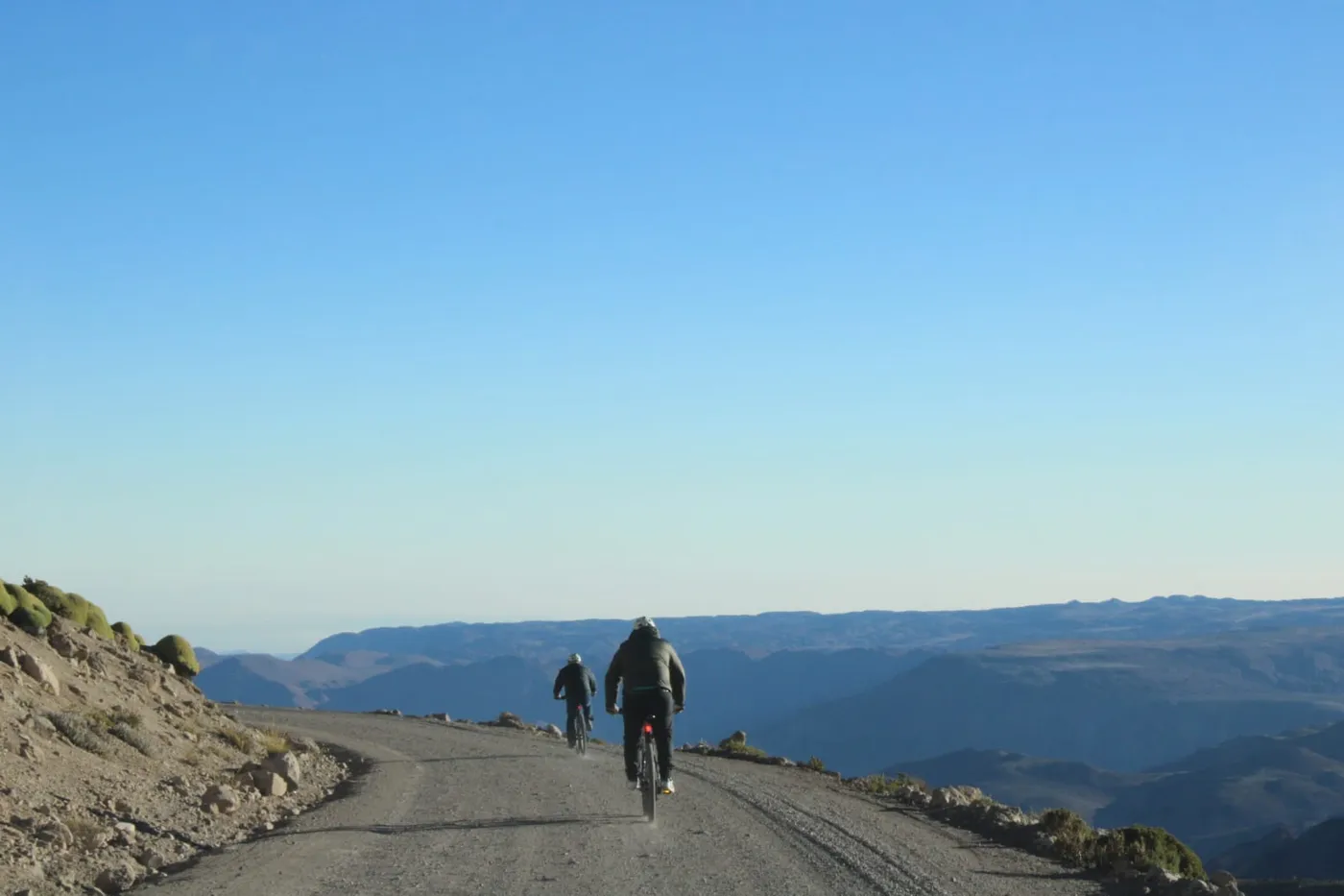 Dos ciclistas pedaleando con vista panorámica de cañones y montañas del altiplano