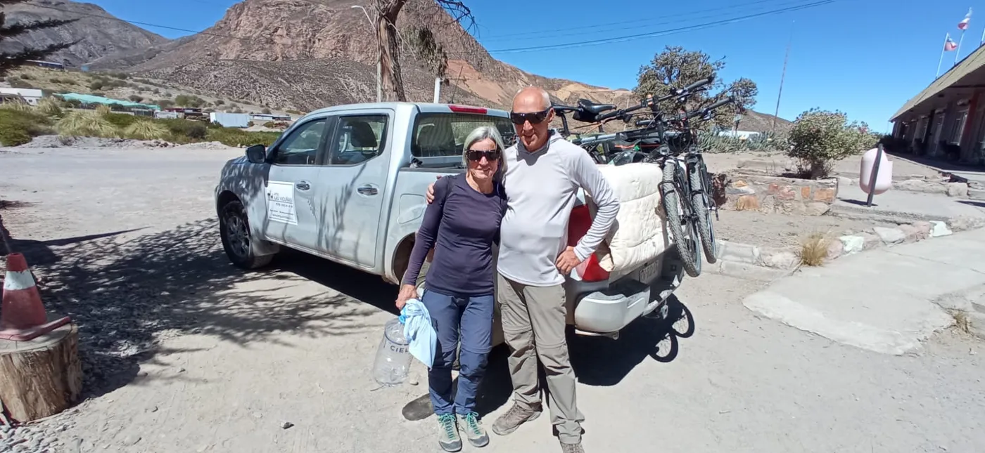Pareja de ciclistas posando junto a la camioneta con las bicicletas montadas en la parrilla